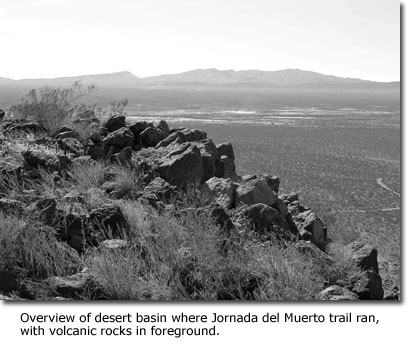Overview of desert basin where Jornada del Muerto trail ran, with volcanic rocks in foreground.