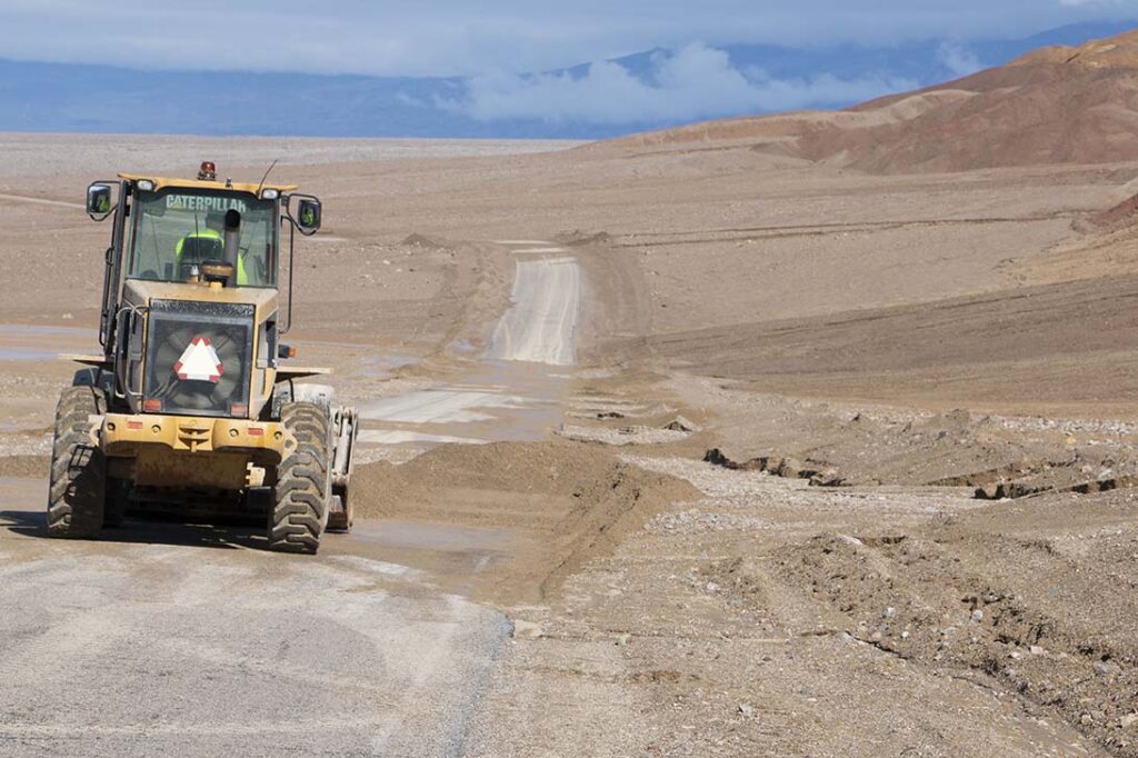 A NPS employee uses a loader to clear flood debris off Badwater Road. NPS/Giovanna Ponce