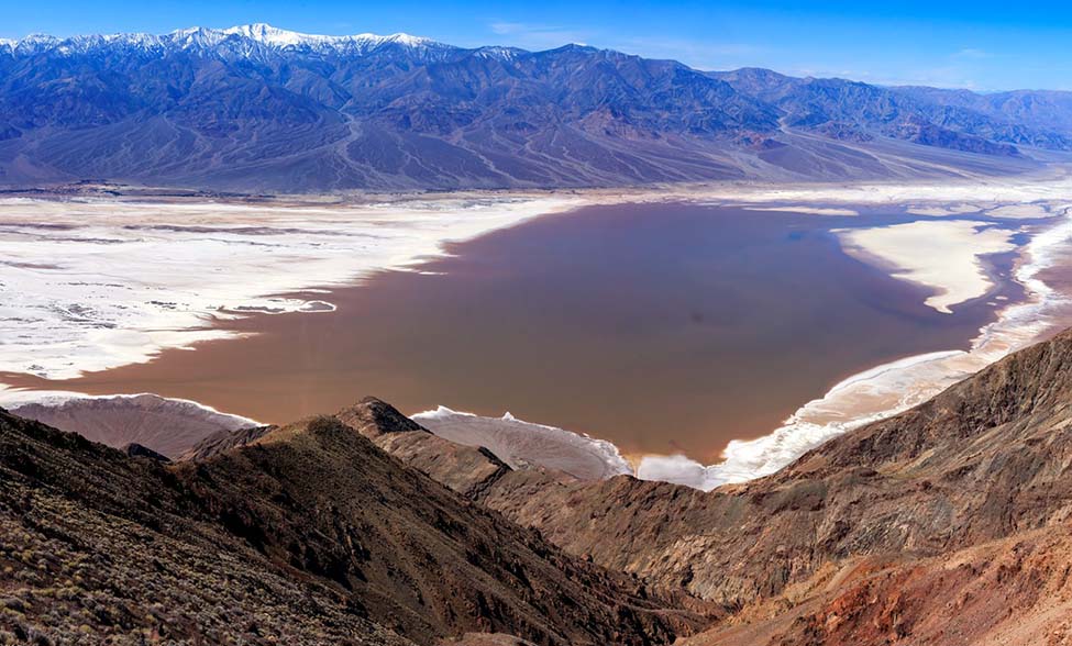Photo taken March 4, 2024 from Dantes View looking down at Badwater Basin. Lake Manly has returned to the pre-wind location, but is now very brown due to mud. NPS/John Hallett