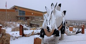 Snow falls on the stegosaurus statue in front of the Quarry Visitor Center. NPS Photo